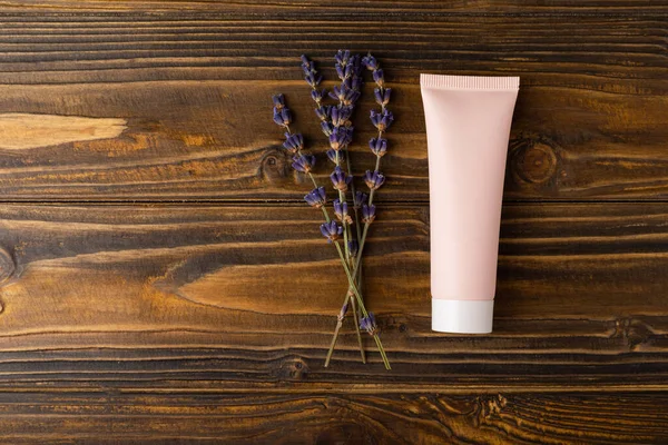 Body cream and lavender flowers on a brown wood background. Spa concept. Place for copy.Place for text