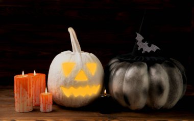 Kahverengi ahşap desenli Cadılar Bayramı balkabağı ve mumlar. Karanlık bir arka planda kompozisyon. Parlayan gözleri ve ağzı olan korkutucu bir kompozisyon. Tatil konsepti. Boşluğu kopyala