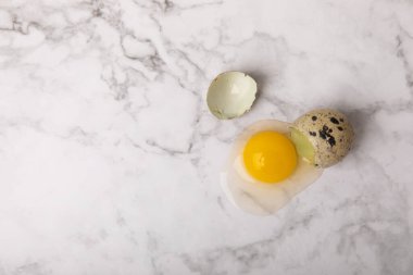 Yüzeyde kırık bıldırcın yumurtası. Beyaz mermer arka planda bıldırcın yumurtaları. Doğal ürünler. Mesaj için yer. taze yumurta