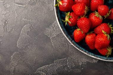 Siyah desenli bir tabakta taze olgun çilekler. Vejetaryen organik böğürtlen. Sağlıklı yiyecek. Vitamin.