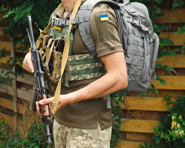 A military man in a military body armor with a tactical Kalashnikov automatic machine gun in his hands. Body armor with combat butts and ammunition. Ukrainian army. Military concept. No war.