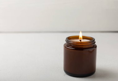 Beyaz desenli kahverengi cam kavanozda yanan mum. Kış evi dekorasyonu. Soya ekolojik mumu. Ev ve iç dekorasyon. Ders için yer..