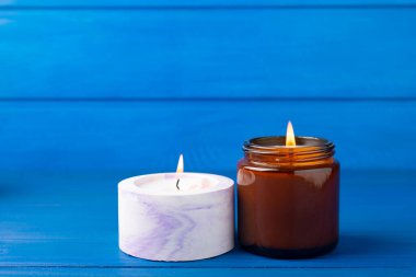 Kahverengi cam bir kavanozda yanan mum ve mavi ahşap bir dokuda beton ekici. Kışın ev dekorasyonu. Soya ekolojik mumu. Ev ve iç dekorasyon. Metin için yer.