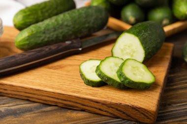 Kahverengi ahşap bir masada taze organik salatalıklar. Salatalık dilimleri. Salata malzemesi. Taze sebzeler. Vejetaryen yemeği. Sağlıklı yiyecekler. Taze organik sebzeler.