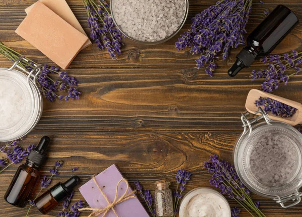 Lavender spa. Sea salt, body scrub, essential oils, lavender flowers and handmade soap. Natural herbal cosmetics with lavender flowers on brown texture wood.Relax concept. Beauty treatments.Copy space