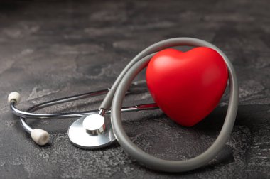 Stethoscope and red decorative heart on black marble background.flat lay.place for text. The concept of cardiology.