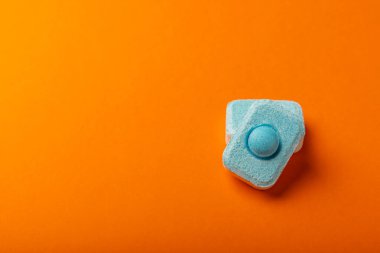 Turuncu arka planda su yumuşatıcı tabletler, düz. Ders için yer. Çamaşır makineleri için kapsüller ve kireç ölçeği önleyen bulaşık makineleri için. Kopyalanacak yer.