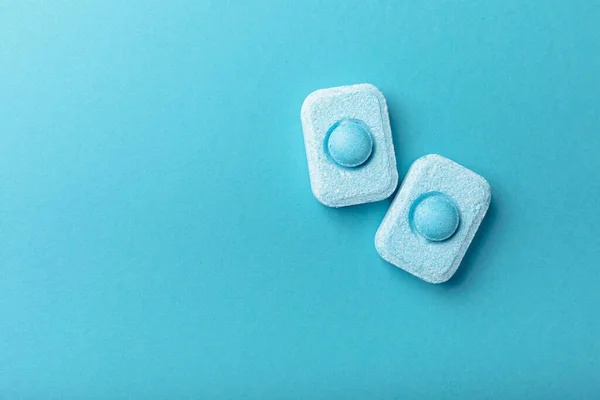 Water softener tablets on a blue background, flat lay. Space for text.Capsules for washing machines and dishwashers that prevent limescale. Place to copy.