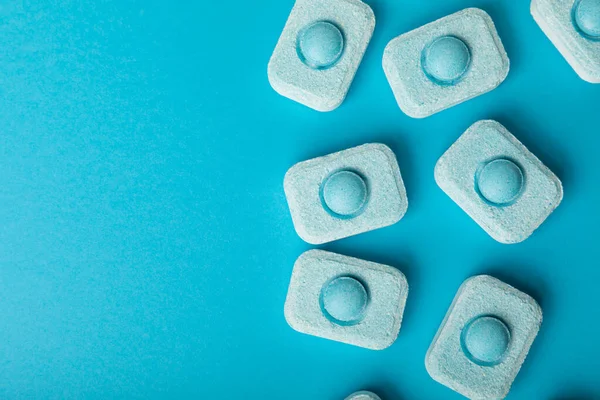 Water softener tablets on a blue background, flat lay. Space for text.Capsules for washing machines and dishwashers that prevent limescale. Place to copy.