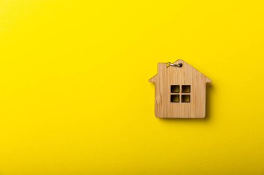 Evin modeli ve anahtarları sarı arka planda, düz yerde. Ev partisi. Gayrimenkul yatırım kavramı. Bir ev almak için para biriktirmeyi planlıyorum. İpotek ve gayrimenkul yatırımı, ev için tasarruf.