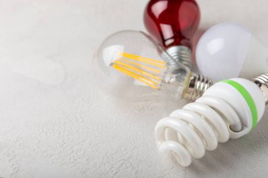 Elektrik ampulleri. Enerji verimliliği kavramı. LED lamba parlak lambaya karşı. Beyaz çimento arka planında kompozisyon. Ekonomik ve çevre dostu bir ampul kavramı kullan.