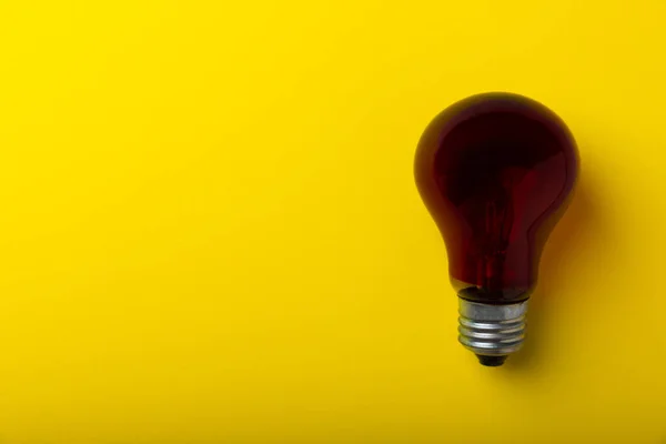 Close-up of a red light bulb on a yellow background. copy space. place for text.