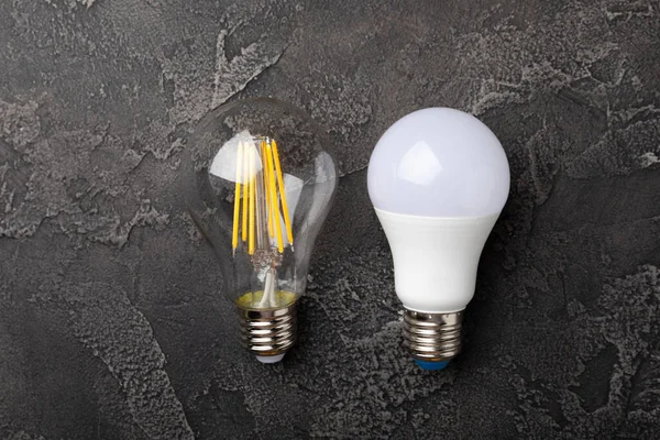 Electric light bulbs. the concept of energy efficiency. LED lamp vs incandescent lamp. Composition on a black marble background. Use an economical and environmentally friendly light bulb concept.