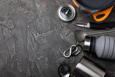 Seyahat ekipmanları siyah mermer zemine ayarlandı. EDC seti. Kamp plakası, bardak, şişe, kaşık ve pusula. Mekanı kopyala.