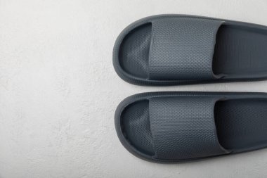 Beyaz tahta arka planda şık lastik terlikler. Değiştirilebilir ayakkabılar. Plaj ayakkabıları. Metin için yer.