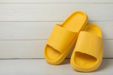 Beyaz tahta arka planda şık lastik terlikler. Değiştirilebilir ayakkabılar. Plaj ayakkabıları. Metin için yer.