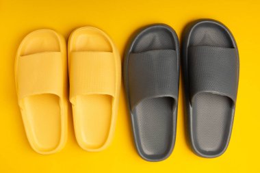 Sarı arka planda bir çift şık lastik terlik. Değiştirilebilir ayakkabılar. Plaj ayakkabıları. Metin için yer.