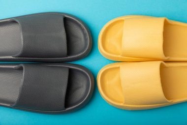 Mavi arka planda bir çift şık lastik terlik. Değiştirilebilir ayakkabılar. Plaj ayakkabıları. Metin için yer.