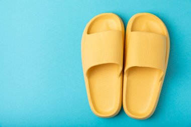 Mavi arka planda şık lastik ayakkabılar. Plaj ayakkabıları. Uzayı kopyala. Metin için yer.