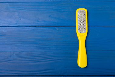 Mavi arka planda ayak ve rendeleyici. Ayak derisi bakım ürünü. Ayağındaki ölü deriyi çıkarmak için sünger taşı dosyası. Bakım ve güzellik konsepti. Boşluğu kopyala.