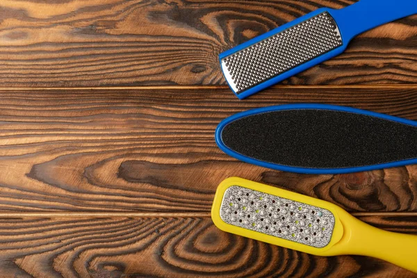 Foot file and grater on brown wooden background. Foot skin care product. Pumice stone file to remove dead skin from feet. Care and beauty concept. Copy space.