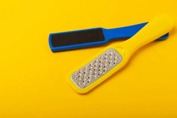 Foot file and grater on yellow background. Foot skin care product. Pumice stone file to remove dead skin from feet. Care and beauty concept. Copy space.