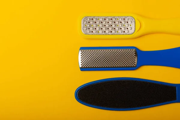 Foot file and grater on yellow background. Foot skin care product. Pumice stone file to remove dead skin from feet. Care and beauty concept. Copy space.