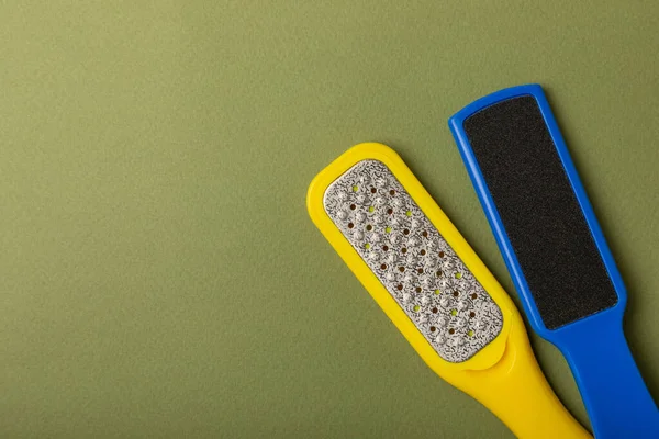 Foot file and grater on green background. Foot skin care product. Pumice stone file to remove dead skin from feet. Care and beauty concept. Copy space.