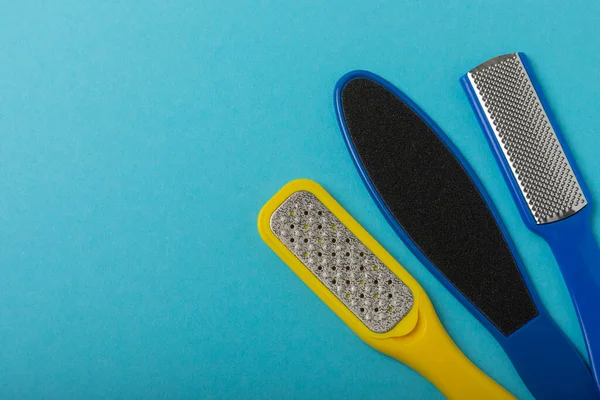 Foot file and grater on a blue background. Foot skin care product. Pumice stone file to remove dead skin from the feet. Care and beauty concept. Copy space.