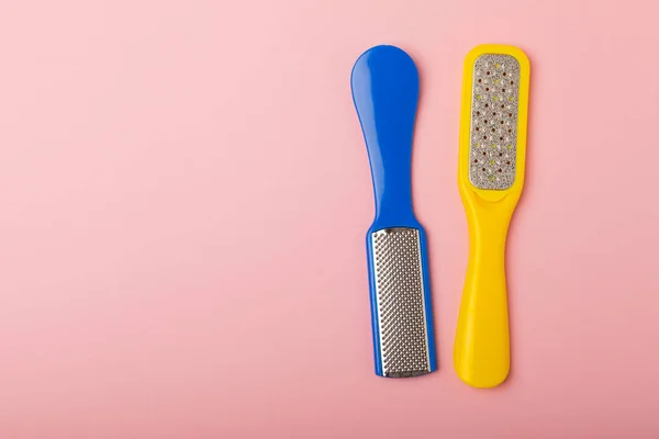 Foot file and grater on pink background. Foot skin care product. Pumice stone file to remove dead skin from feet. Care and beauty concept. Copy space.