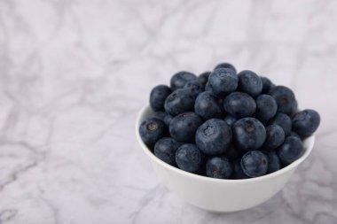 Beyaz mermer arka planda yaban mersini kasesi. Olgun ve taze yaban mersini. Vitaminler. Sağlıklı yiyecekler. Meyve suyu. Uzayı kopyala Metin için yer