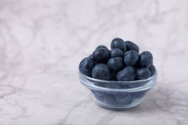 Beyaz mermer arka planda yaban mersini kasesi. Olgun ve taze yaban mersini. Vitaminler. Sağlıklı yiyecekler. Meyve suyu. Uzayı kopyala Metin için yer