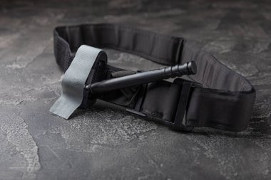 Siyah dokulu arka plandaki kanı durdurmak için tıbbi turnike. Kopyalanacak yer. düz döşek.