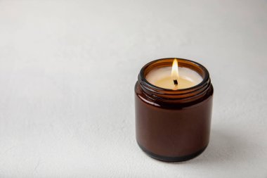 Beyaz desenli kahverengi cam kavanozda yanan mum. Kış evi dekorasyonu. Soya ekolojik mumu. Ev ve iç dekorasyon. Ders için yer..