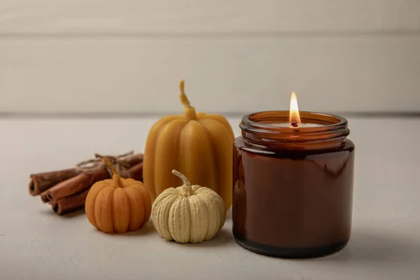 Cozy autumn pumpkin candles on white wood texture.Autumn Halloween home decor.Soy ecological candle.Halloween pumpkin candles.Home and interior decoration.Place for text.Copy space.