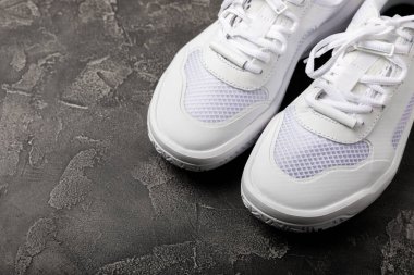 Siyah desenli arka planda beyaz ayakkabılar. Moda. UNISEX. Aktif yaşam tarzı için spor ayakkabıları. Ürün fotoğrafı ve kaldırma konsepti. Sokak stili. Metin için yer..