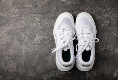 Siyah desenli arka planda beyaz ayakkabılar. Moda. UNISEX. Aktif yaşam tarzı için spor ayakkabıları. Ürün fotoğrafı ve kaldırma konsepti. Sokak stili. Metin için yer..