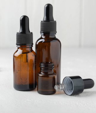 Essential oil in a glass bottle with a pipette. Bottle with fragrant oil on a white wooden background. essential oil mockup with copy space. serum.