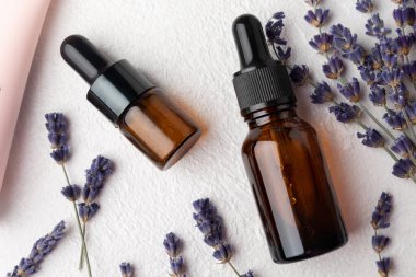 Essential oil of lavender on a white texture background. Spa concept. RELAX. Bottle with fragrant oil and lavender flowers.Aromatic oil with lavender scent.mockup of lavender essential oil.Copy space.