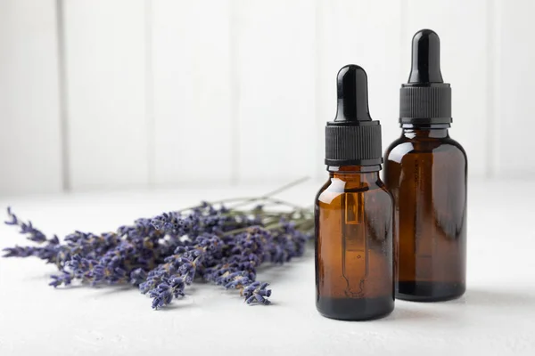 Essential oil of lavender on a white texture background. Spa concept. RELAX. Bottle with fragrant oil and lavender flowers.Aromatic oil with lavender scent.mockup of lavender essential oil.Copy space.