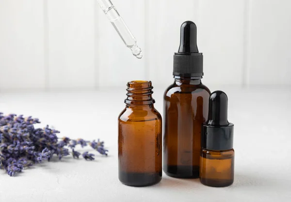 Essential oil of lavender on a white texture background. Spa concept. RELAX. Bottle with fragrant oil and lavender flowers.Aromatic oil with lavender scent.mockup of lavender essential oil.Copy space.