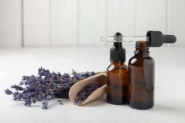 Essential oil of lavender on a white texture background. Spa concept. RELAX. Bottle with fragrant oil and lavender flowers.Aromatic oil with lavender scent.mockup of lavender essential oil.Copy space.