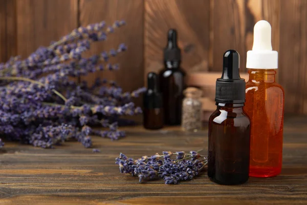 Essential oil of lavender on a brown background. Spa concept. RELAX. Bottle with fragrant oil and lavender flowers.Aromatic oil with lavender scent.mockup of lavender essential oil.Copy space. Place for text.