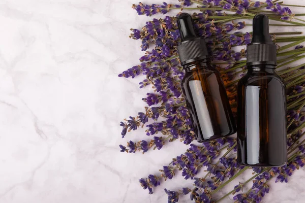 Essential oil of lavender on a white texture background. Spa concept. RELAX. Bottle with fragrant oil and lavender flowers.Aromatic oil with lavender scent.mockup of lavender essential oil.Copy space.