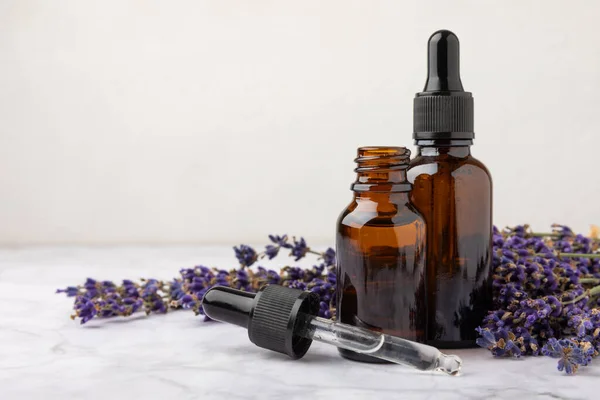 Essential oil of lavender on a white texture background. Spa concept. RELAX. Bottle with fragrant oil and lavender flowers.Aromatic oil with lavender scent.mockup of lavender essential oil.Copy space.