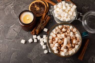 Bir fincan lezzetli kakao içeceği ve mavi bardakta şekerlemeler. Siyah dokuma masasında kış içecekleri için marşmelovlar ve şekerlemeler. Kış sıcak içeceği..