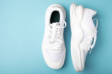 White sneakers on a blue background.Fashion.UNISEX. Sneakers are sports shoes for an active lifestyle. Product photo and levitation concept. Street style. Copy space. Place for text.
