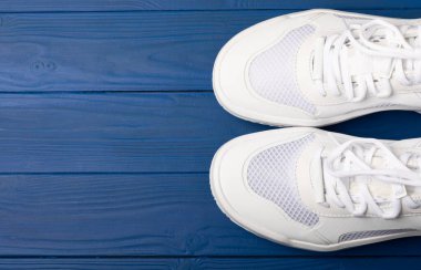  White sneakers on a blue background.Fashion.UNISEX. Sneakers are sports shoes for an active lifestyle. Product photo and levitation concept. Street style. Copy space. Place for text.