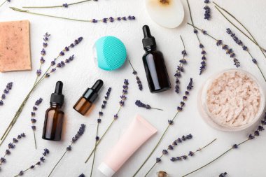 Lavender spa. Sea salt, lavender flowers, body scrub and cream and handmade soap. Natural herbal cosmetics with lavender flowers on white texture background.