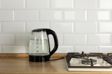 Modern electric transparent kettle on a wooden table in the kitchen.Kettle for boiling water and making tea.Home appliances for making hot drinks.Space for copy.Place for text.